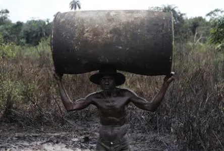 Ebiowei, 48, carries an empty oil container on his head to a place where it would be filled with refined fuel at an illegal refinery site